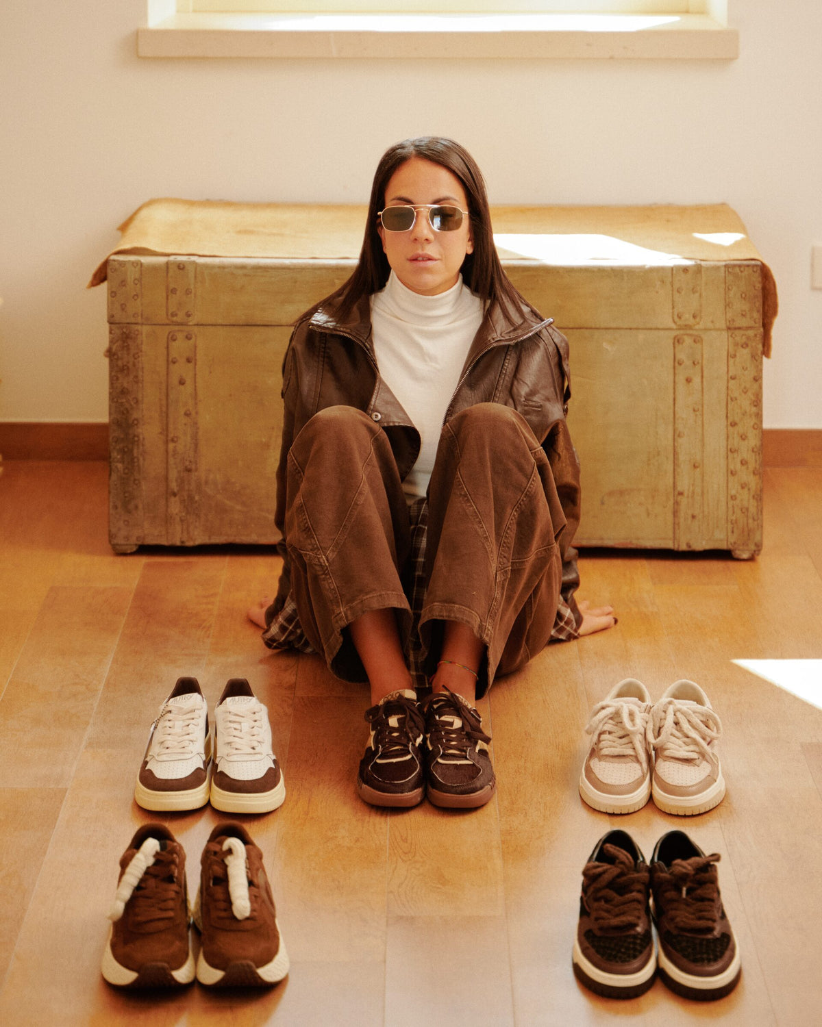 Ragazza seduta con quattro paia di sneakers davanti a sé