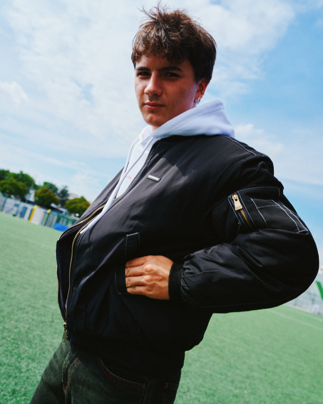 Ragazzo con giubbotto bomber nero su un campo da calcio